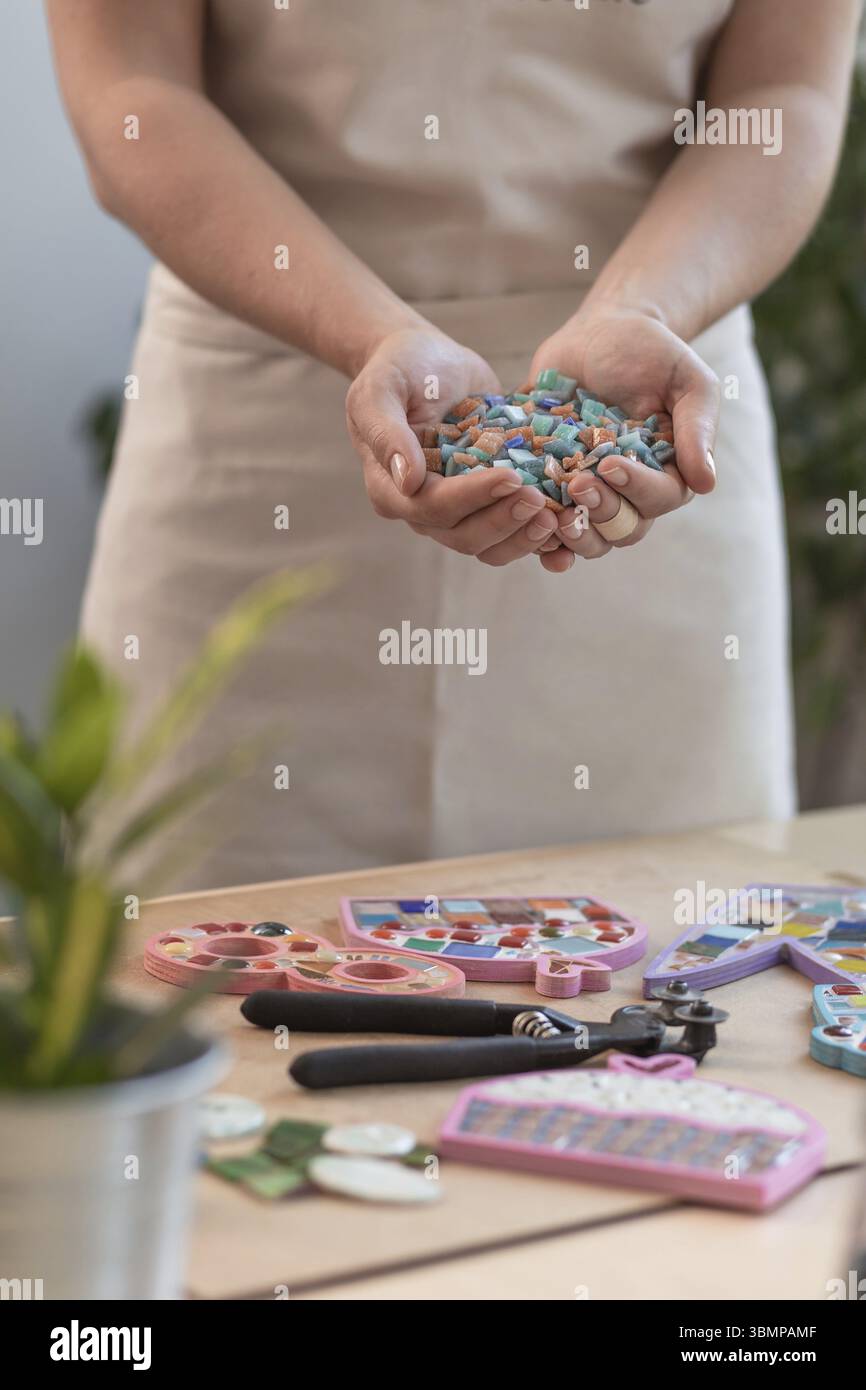 Lieu de travail de la mosaïque maître : women's hands holding détails mosaïque dans le processus de création d'une mosaïque. Close-up Banque D'Images