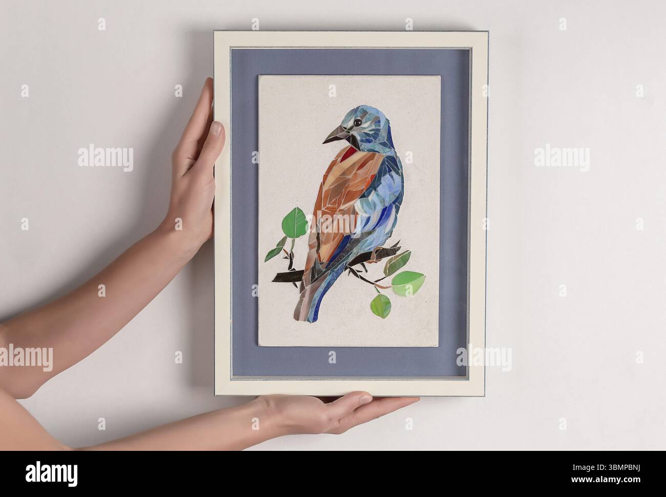 Femme tenant dans les mains image de mosaïque dans un cadre. Gros plan Banque D'Images