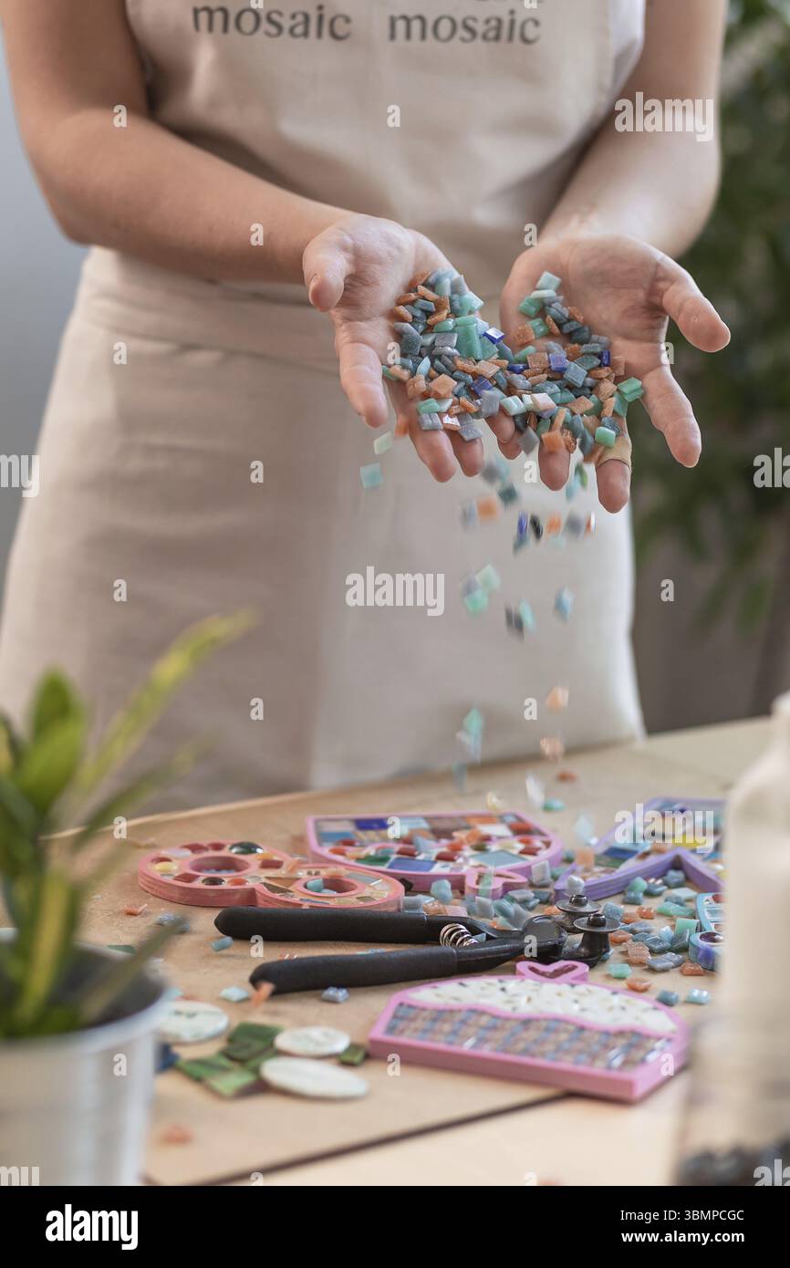 Lieu de travail de la mosaïque maître : women's hands holding détails mosaïque dans le processus de création d'une mosaïque. Close-up Banque D'Images