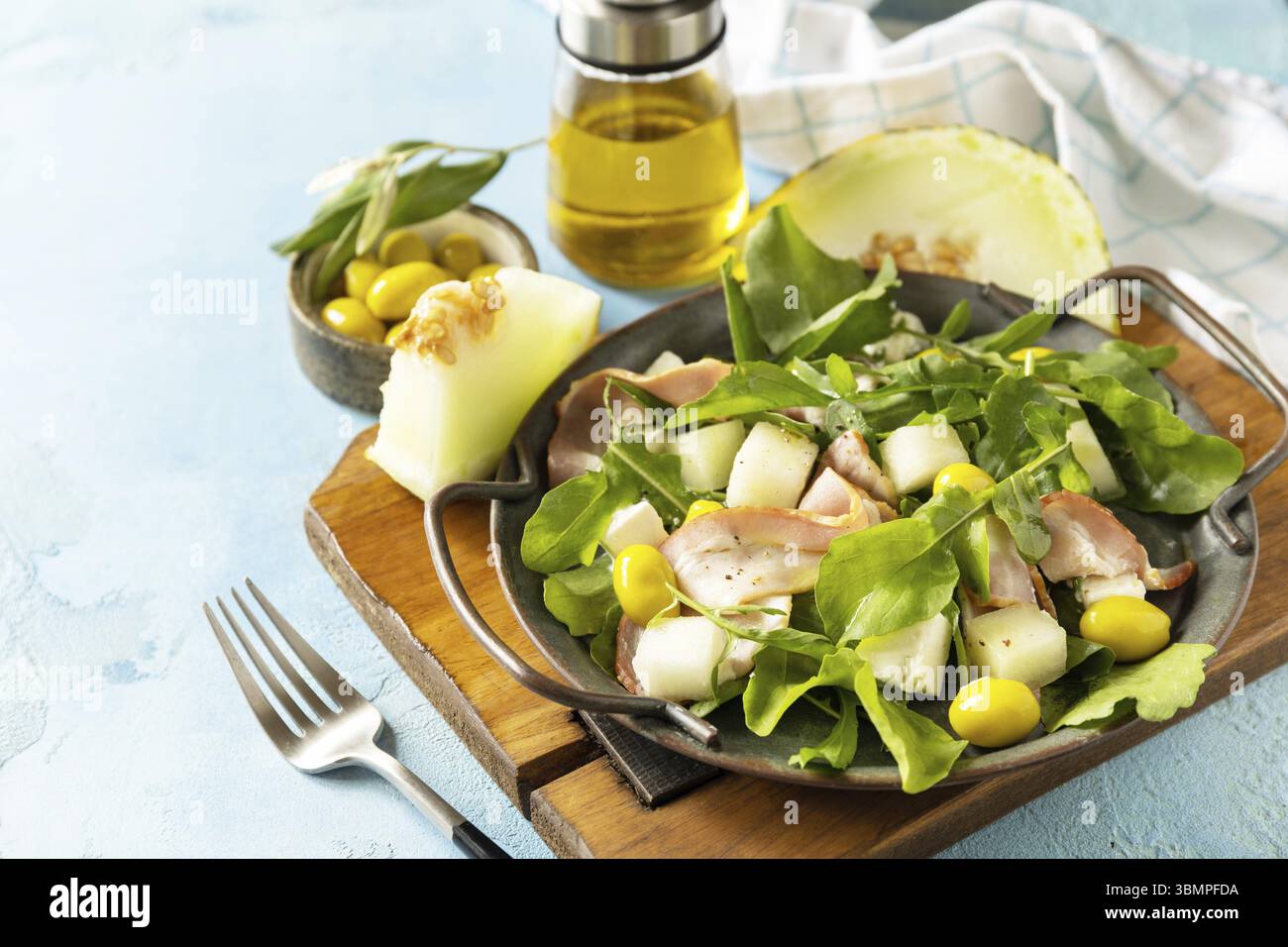 Apéritif traditionnel espagnol et italien. Salade méditerranéenne d'été avec melon, bacon, olives, fromage blanc et roquette sur fond de pierre bleue. Co Banque D'Images