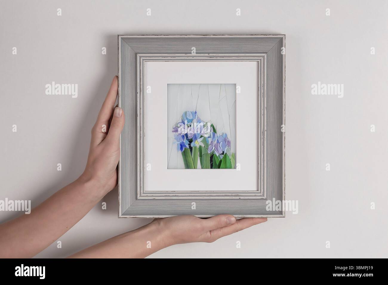 Femme tenant dans les mains image de mosaïque dans un cadre. Gros plan Banque D'Images
