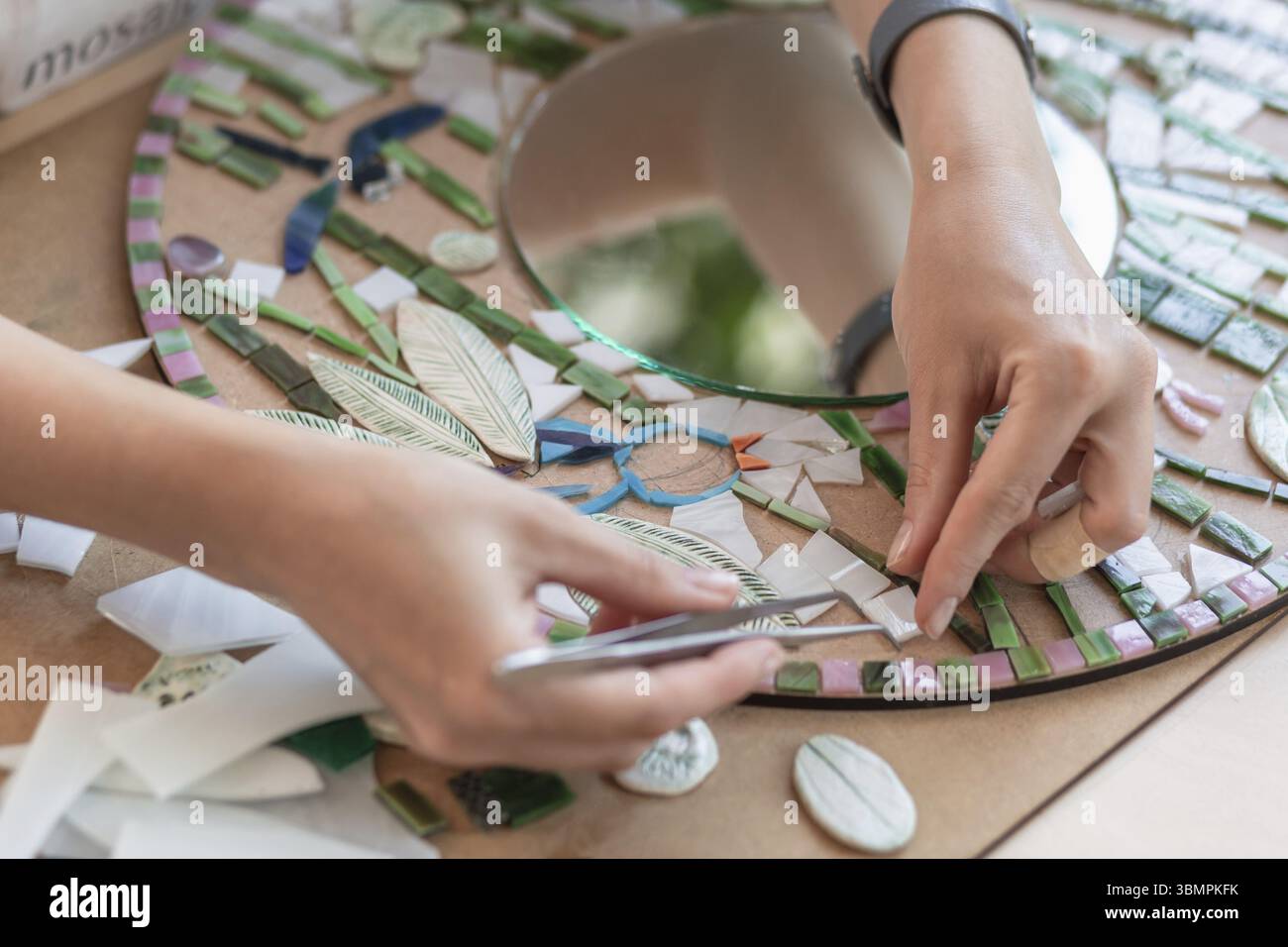 Lieu de travail de la mosaïque maître : women's hands holding tool pour mosaic détails dans le processus de création d'une mosaïque. Close-up. Processus de création. Mastercla Banque D'Images