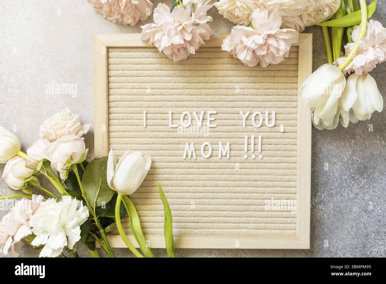 Bonne fête des mères. Lettre J'AIME MOM sur le carton et belles fleurs de printemps sur fond clair. Carte de voeux pour la fête des femmes, le mariage et la fête des mères. Banque D'Images