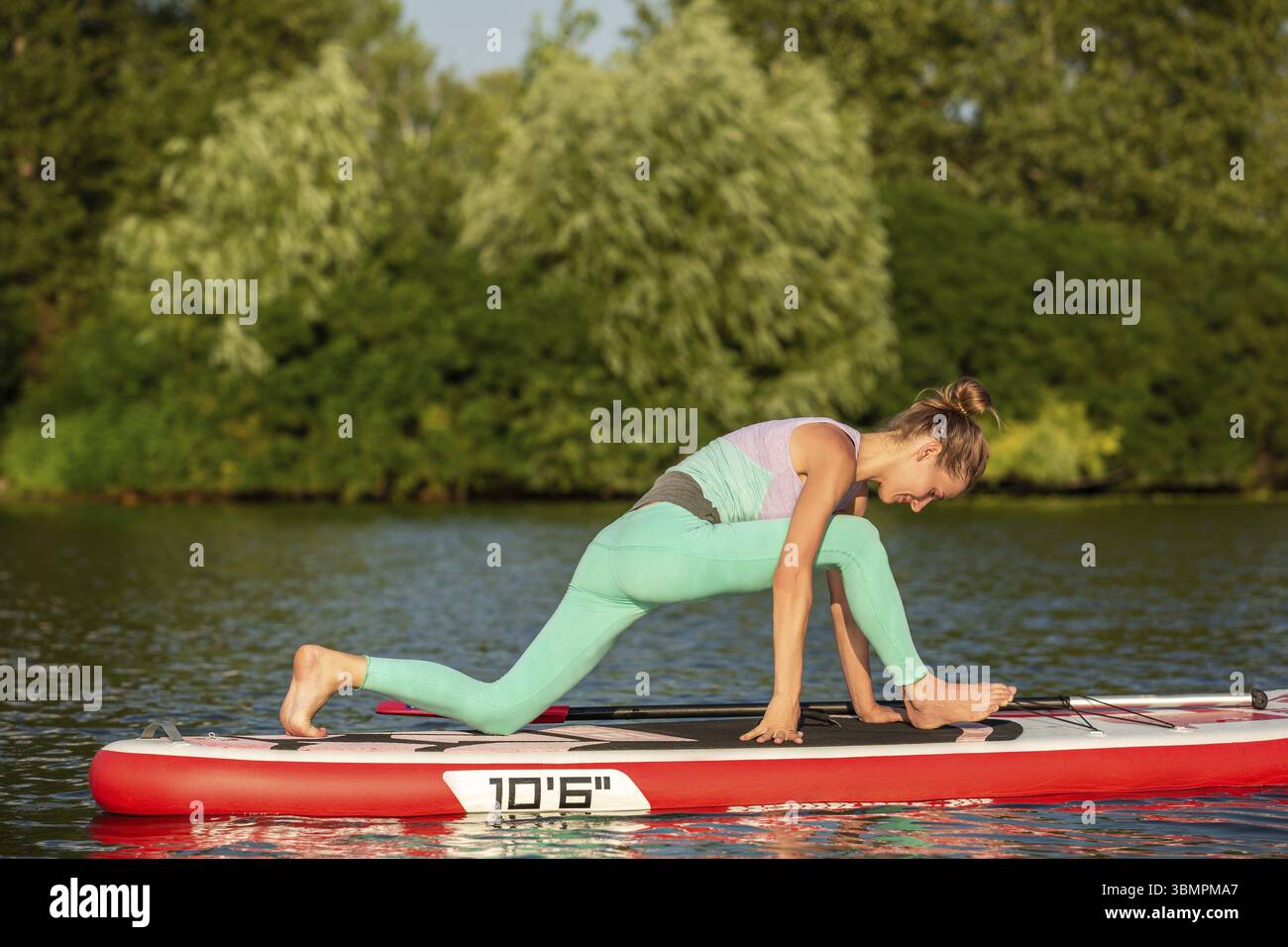 Femme pratiquant le yoga sur le paddle board le matin. Sport. Passe-temps. Yoga Banque D'Images