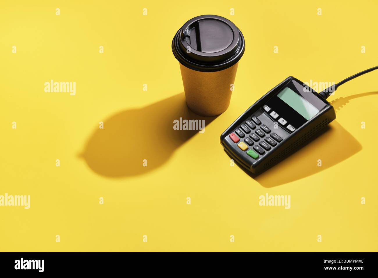 Terminal de paiement POS et café sur fond jaune. Concept de service financier minimal. Ombres à la mode, espace de copie Banque D'Images