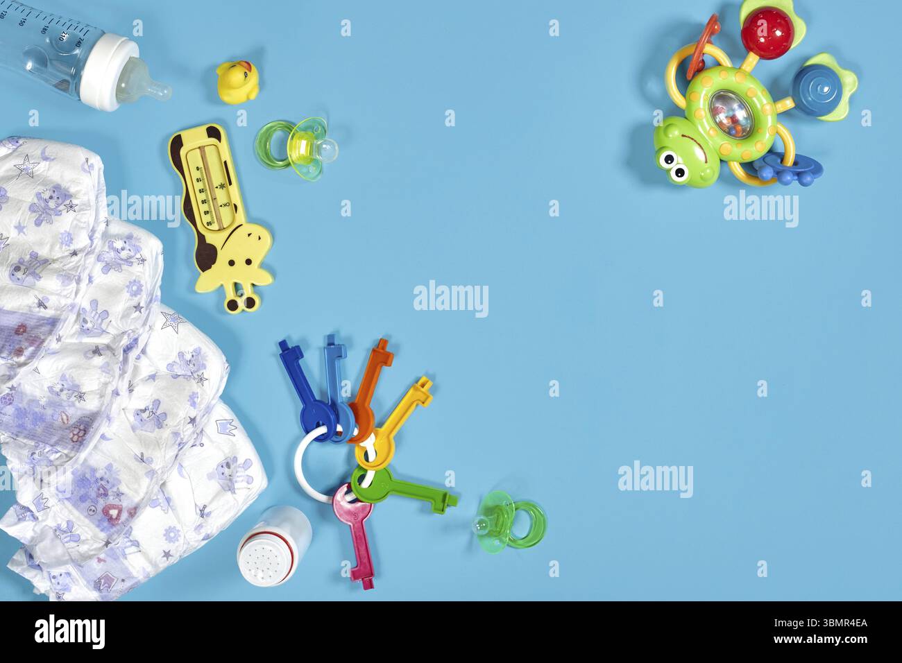 Produits pour bébés : couche en tissu, poudre pour bébé, grignoteuse, crème, anneau de dentition, sucette, jouet de bébé sur fond bleu. Copier l'espace. Vue de dessus. Le développement de la petite enfance Banque D'Images