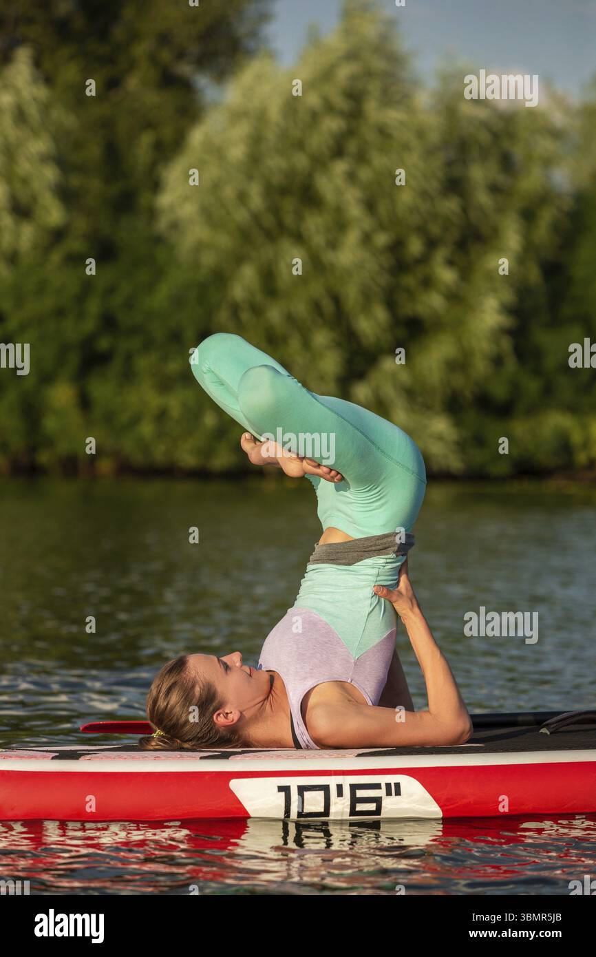 Femme pratiquant le yoga sur le paddle board le matin. Sport. Passe-temps. Yoga Banque D'Images