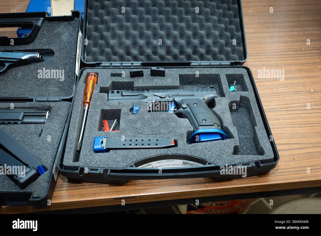 Landkreis Osnabrück, Deutschland 25. Juni 2025 : Im Bild : Ine moderne Walther Sportpistole, eine hochpräzise Kurzhandwaffe für den Wettkampfsport, liegt sicher in einem geöffneten, gepolsterten Transportkoffer. Die Pistole ist schwarz mit auffälligen blauen Akzenten am Griff und Magazin, was auf ein spezialisiertes Wettkampfmodell hindeutet. Neben der Pistole sind im Schaumstoff-Inlay des Koffer weitere Zubehörteile wie ein langes Magazin, ein Schraubendreher und kleine blaue Werkzeuge oder Ersatzteile präzise angeordnet. Der Koffer gewährleistet den sicheren transport und die geschützte Aufbe Banque D'Images