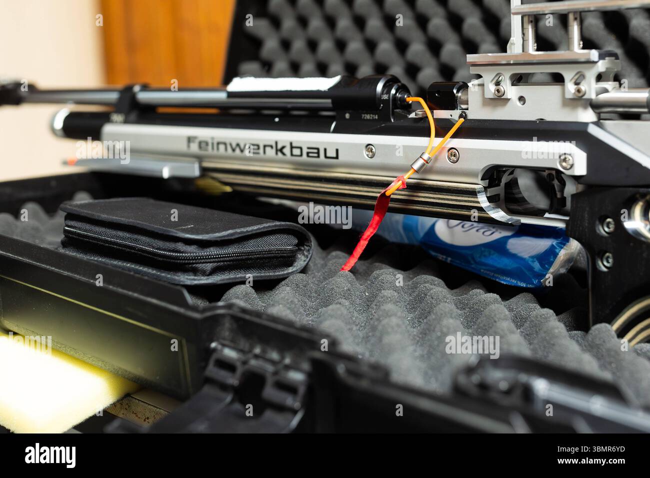 Landkreis Osnabrück, Deutschland 25. Juni 2025 : Im Bild : eine Nahaufnahme zeigt ein Feinpfeilbau Sportgewehr, das auf einem geöffneten, gepolsterten Waffenkoffer liegt. Der Fokus liegt auf der detailreichen Mechanik des Gewehrs, insbesondere auf dem Bereich des Verschlusses. Ein gut sichtbarer roter Faden dient als Ladezustandsanzeiger und signalisiert unmissverständlich, dass sich keine Patrone im Lauf befindet. Diese wichtige Sicherheitsmaßnahme ist typisch für den verantwortungsvollen Umgang im Schießsport. Die Aufschrift Feinwerkbau auf dem Gewehr ist klar erkennbar, was die Qualität des S. Banque D'Images