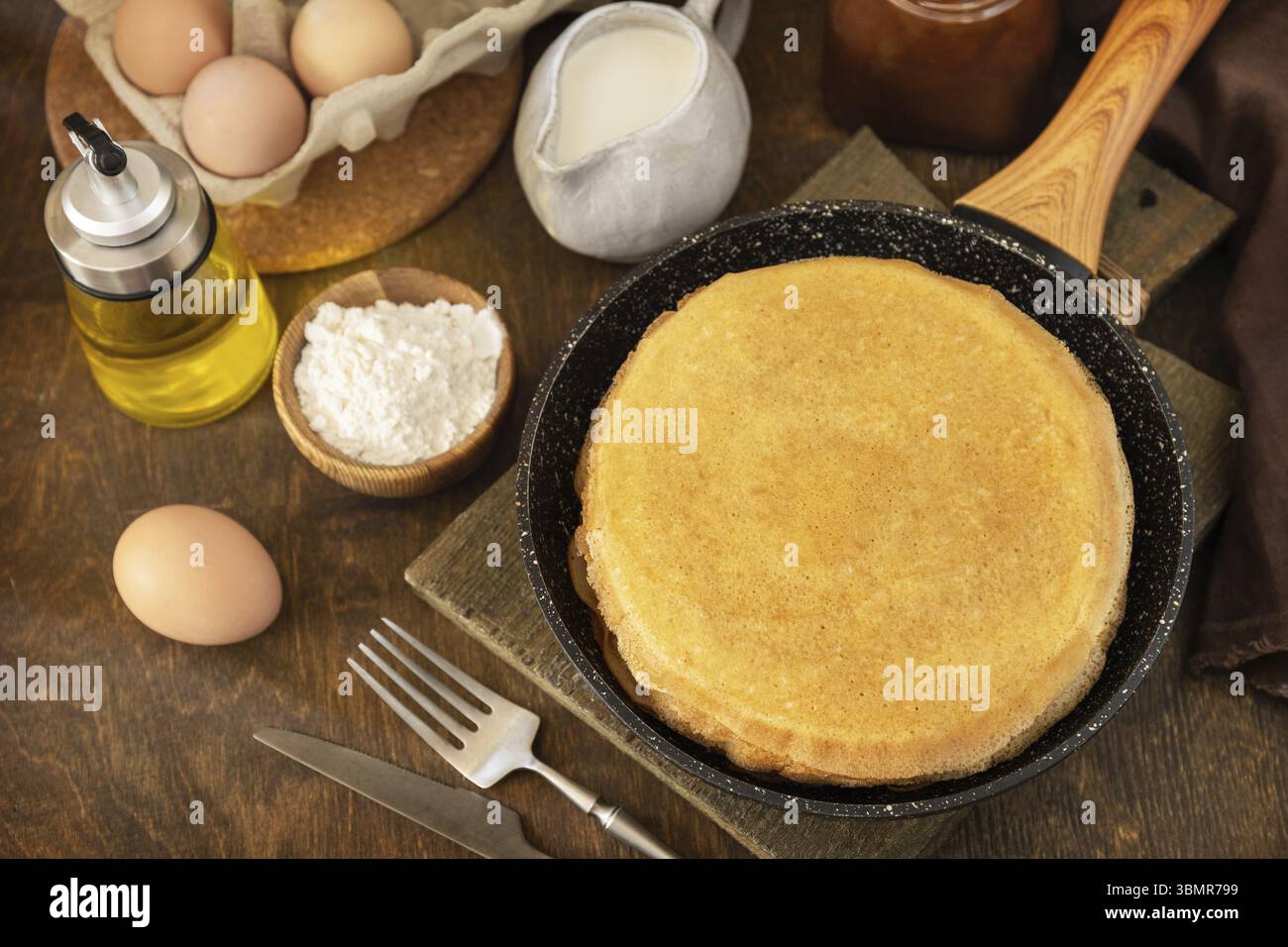 Célébrer la journée des crêpes, cuisiner un petit déjeuner sain. Délicieuses crêpes ou crêpes maison dans une poêle et ingrédients sur une table rustique Banque D'Images