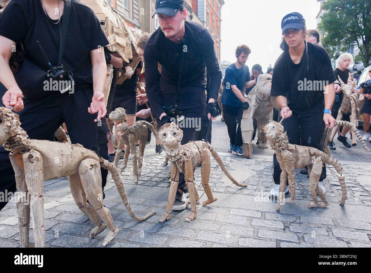 Londres, Royaume-Uni. 27 juin 2025. The Herds, une initiative d’art public et d’action climatique dans laquelle des animaux marionnettes grandeur nature créés à partir de matériaux recyclés parcourent 20 000 km du bassin du Congo au cercle arctique, symbolisant leur fuite des catastrophes climatiques à travers les villes d’Afrique et d’Europe. Sur la photo : les marionnettistes manipulent des marionnettes de singes alors que les troupeaux se fraient un chemin dans les rues de Covent Garden dans le centre de Londres. Banque D'Images