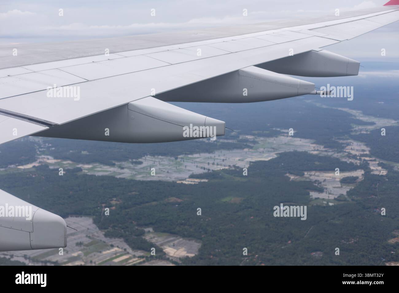 Avion volant au-dessus de terres agricoles et de forêts – gros plan de l'escadre de l'avion avec des moteurs vus de la fenêtre passager en vol Banque D'Images
