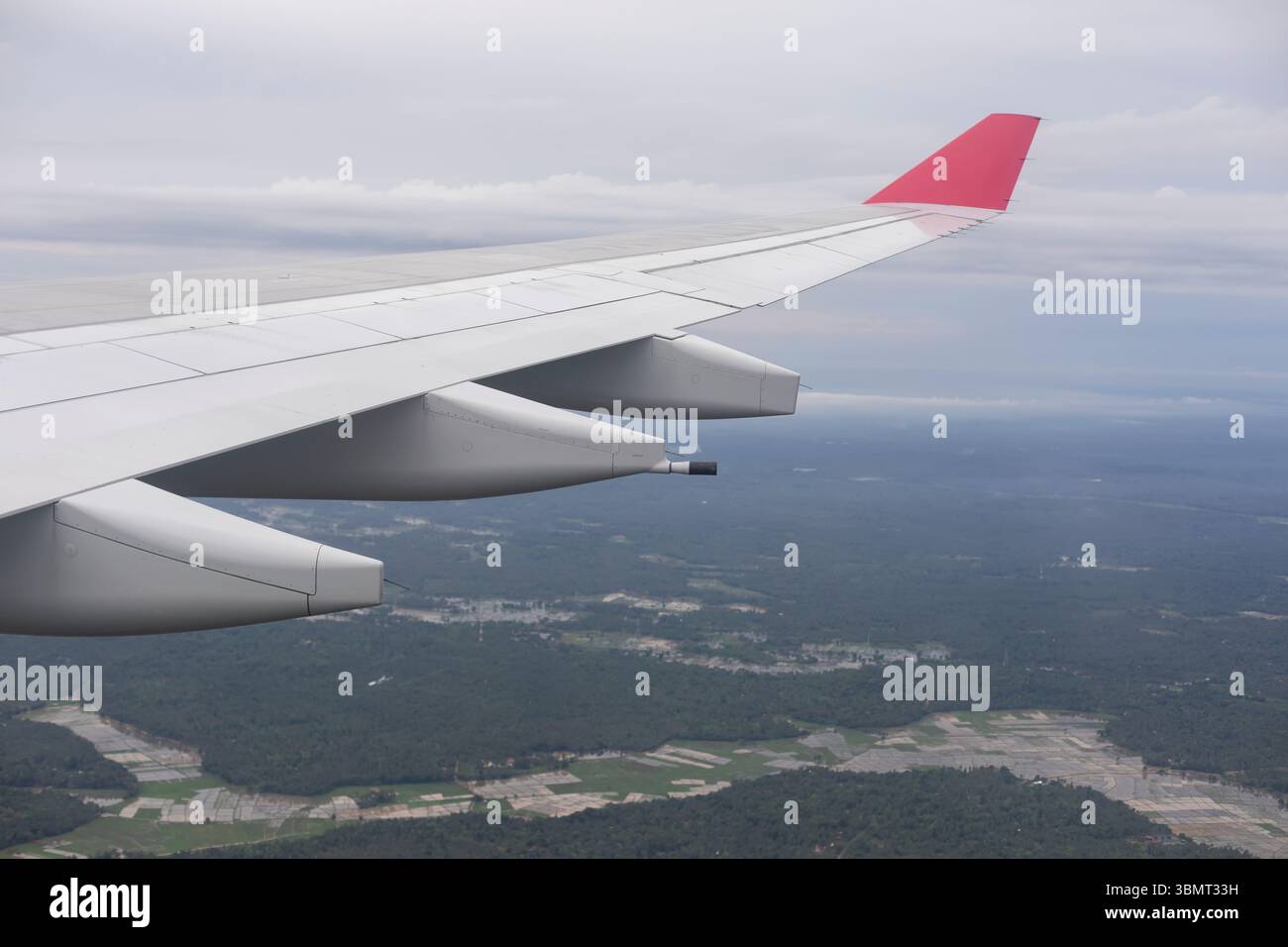 Vue aérienne depuis la fenêtre plane – aile et moteurs de l'avion avec terrain tropical, forêts et champs Paddy en arrière-plan Banque D'Images