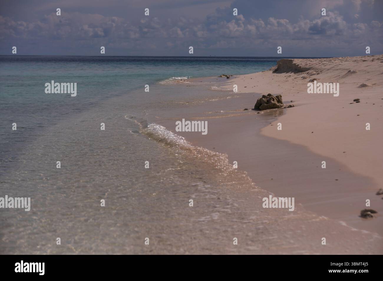 Littoral des Maldives avec des vagues cristallines et du sable de plage lisse sous le ciel nuageux - Scenic Island Coast pour les thèmes voyage et nature Banque D'Images