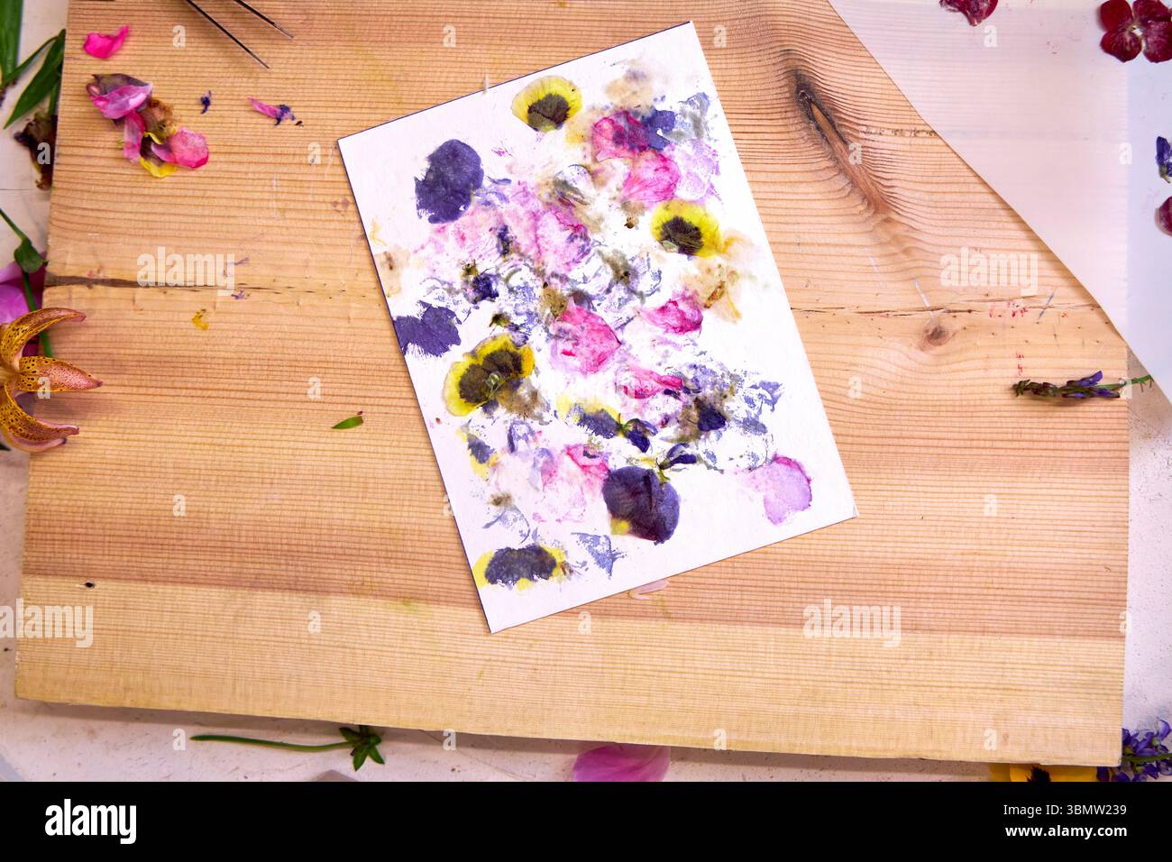 Carte d'impression florale avec texte estampillé « Be Happy » – art botanique fait à la main avec pigments de fleurs, tampon d'encre, lettres en bois et décor naturel, vue de dessus Banque D'Images