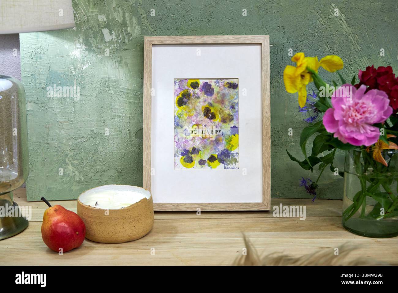 Imprimé botanique encadré avec texte « Be Happy » affiché dans un intérieur confortable – pigments de fleurs naturels, œuvres d'art florales faites à la main, décoration murale rustique Banque D'Images