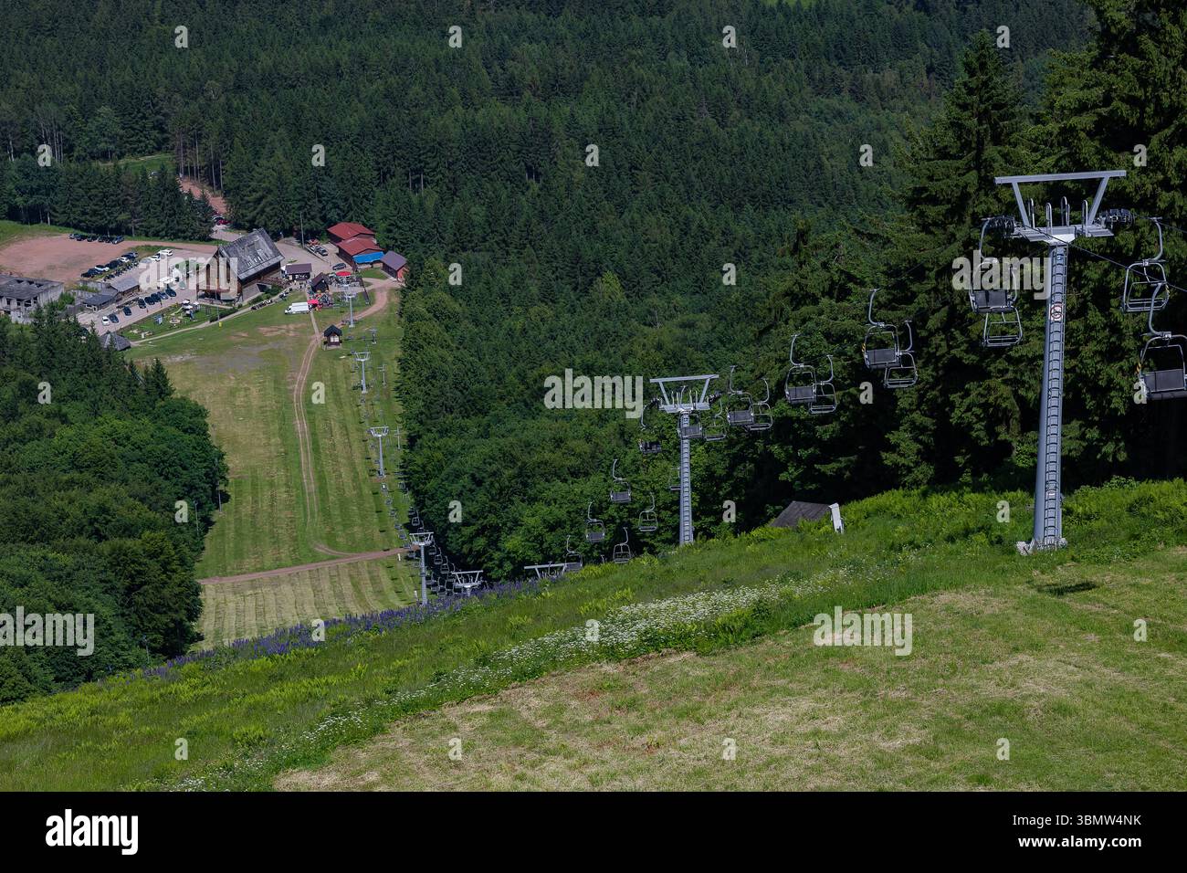 Station de montagne avec sentiers de randonnée et télésiège vide parmi les pentes boisées et les prairies alpines. Aventures de randonnée et loisirs de montagne en plein air Banque D'Images