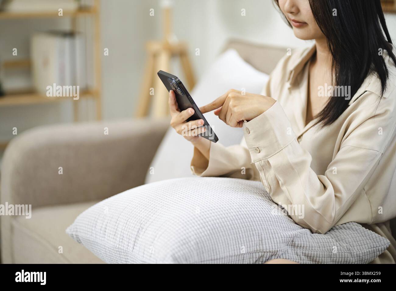 Fille asiatique utilisant un téléphone portable pour vérifier les médias sociaux à la maison tenant smartphone le matin Banque D'Images