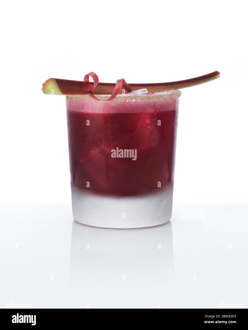 Cocktail dans un gobelet sur glace avec tige de rhubarbe comme garniture sur fond blanc, studio shot Banque D'Images