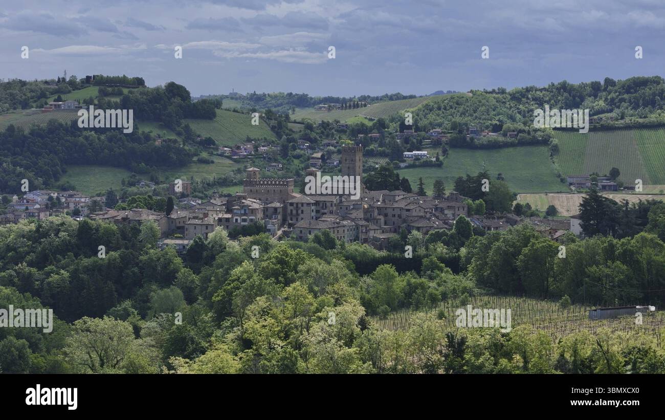 Castell'Arquato médiéval niché parmi les collines verdoyantes de Piacenza, entouré de vignobles luxuriants et d'une végétation dense sous un ciel nuageux couvant Banque D'Images
