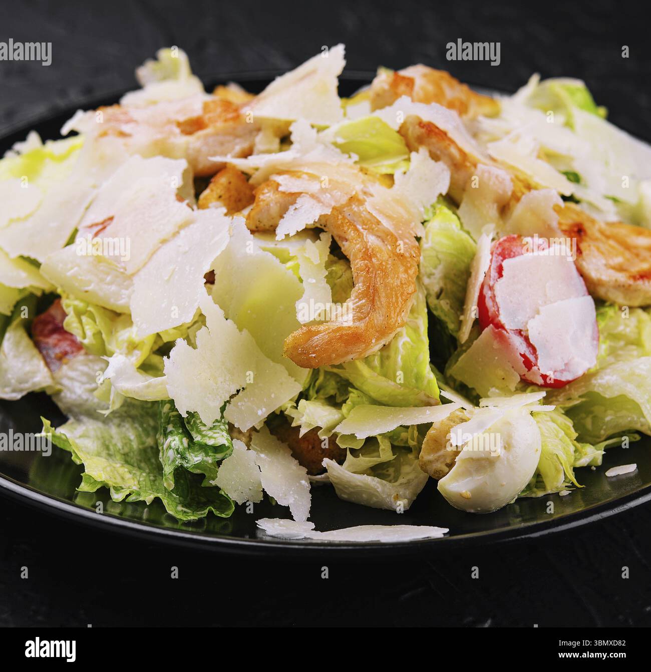 Nature morte, délicieuse salade césar fraîche sur assiette noire Banque D'Images