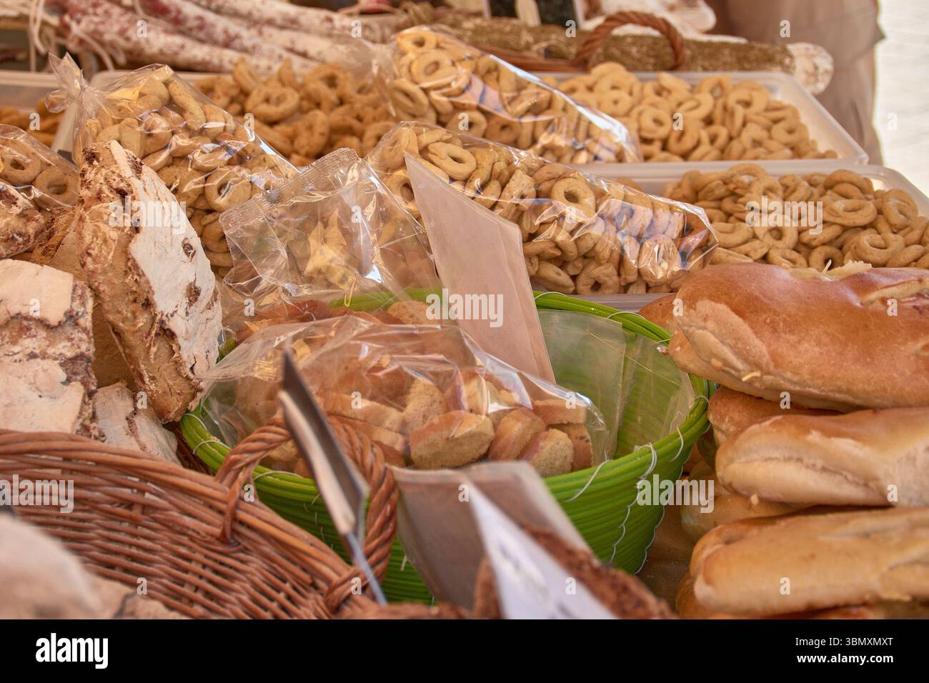 Des produits de boulangerie rustiques soigneusement disposés sur un étal de marché à Aix, en Provence, avec des pains emballés, des beignets et des biscuits. Banque D'Images