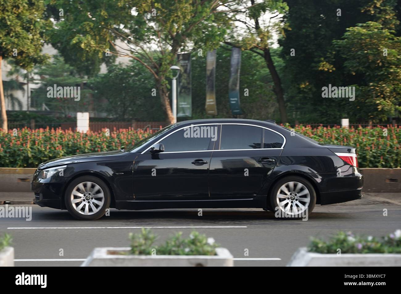 Berline de luxe BMW série 5, conduite de couleur noire dans le quartier des affaires, Sudirman Street, Jakarta, Indonésie Banque D'Images