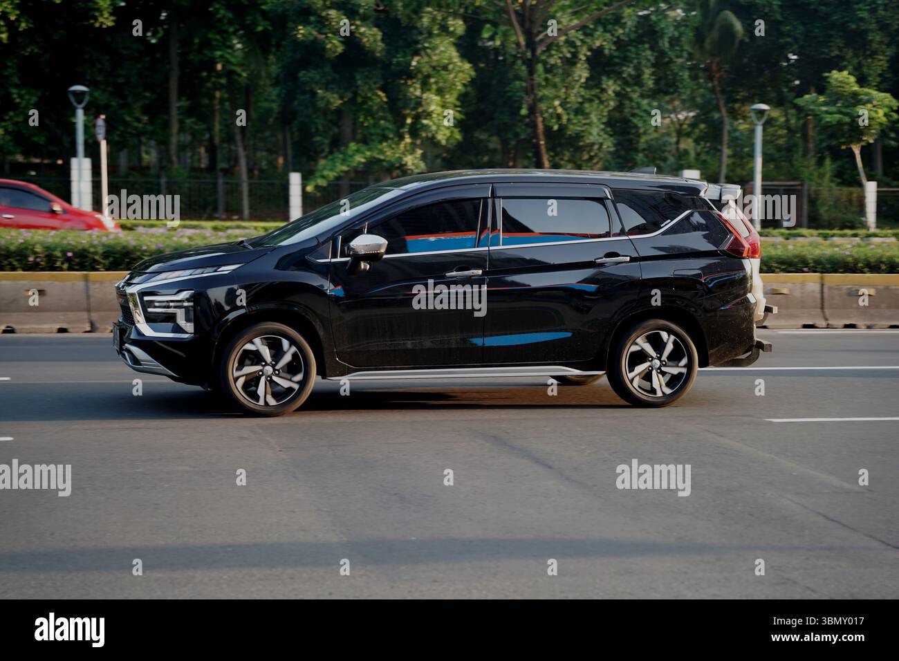 Monospace Mitsubishi Xpander, route de couleur noire dans le quartier des affaires, Sudirman Street, Jakarta, Indonésie Banque D'Images