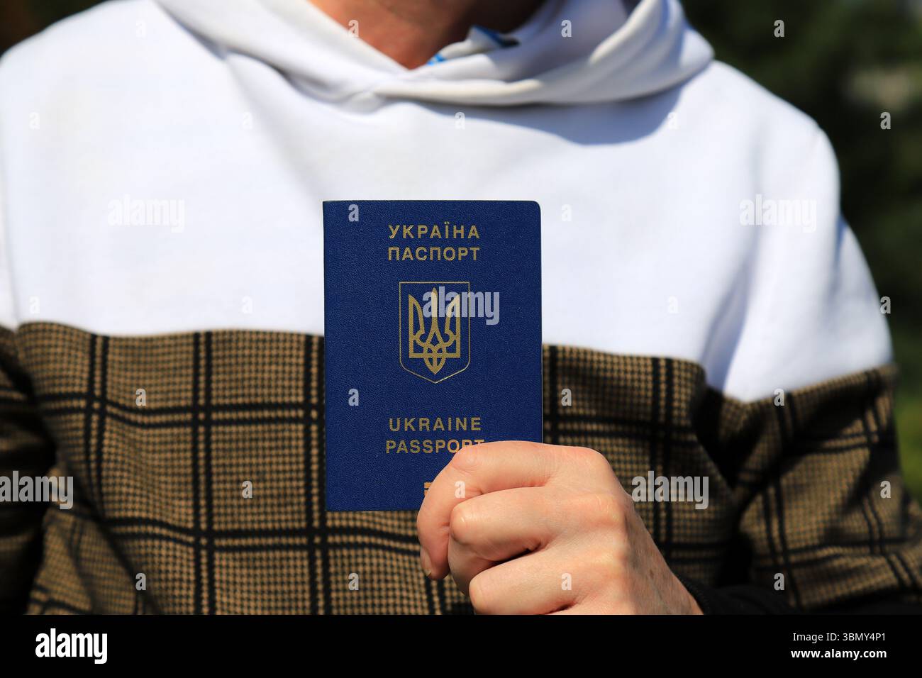 L'homme tient dans les mains passeport avec inscription en ukrainien - passeport de l'Ukraine et emblème d'État de l'Ukraine. Concept voyage, réfugié, touriste, émigré Banque D'Images