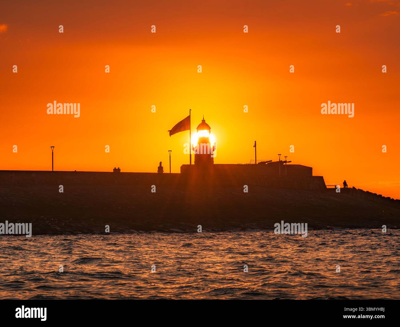Coucher de soleil aligné avec le phare de Dún Laoghaire avec Goat Boat Tours Banque D'Images