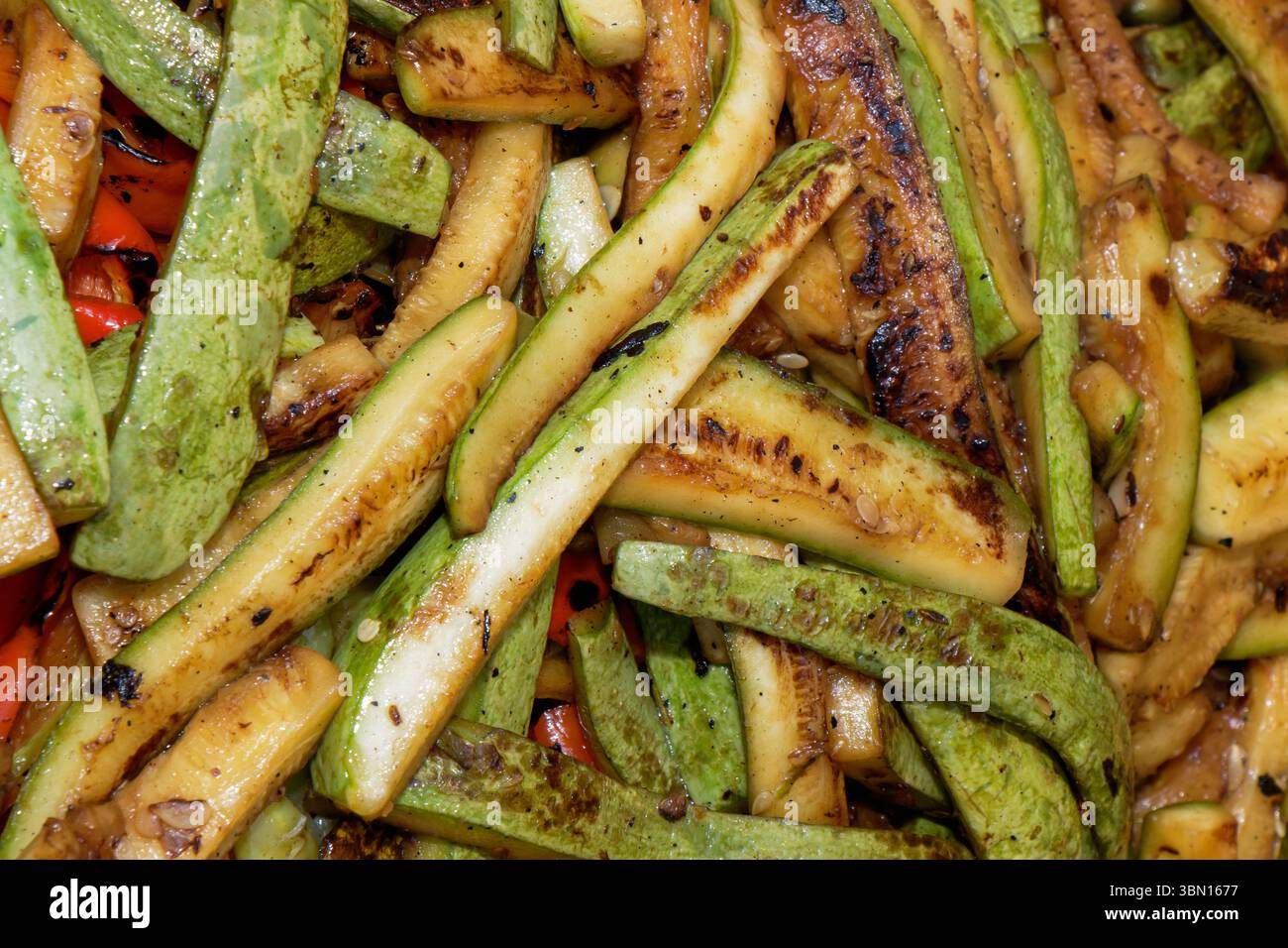 Des courgettes et des poivrons fraîchement grillés sont préparés pour être servis lors d'un barbecue d'été. Les couleurs vives et les bords carbonisés indiquent qu'ils sont bursti Banque D'Images