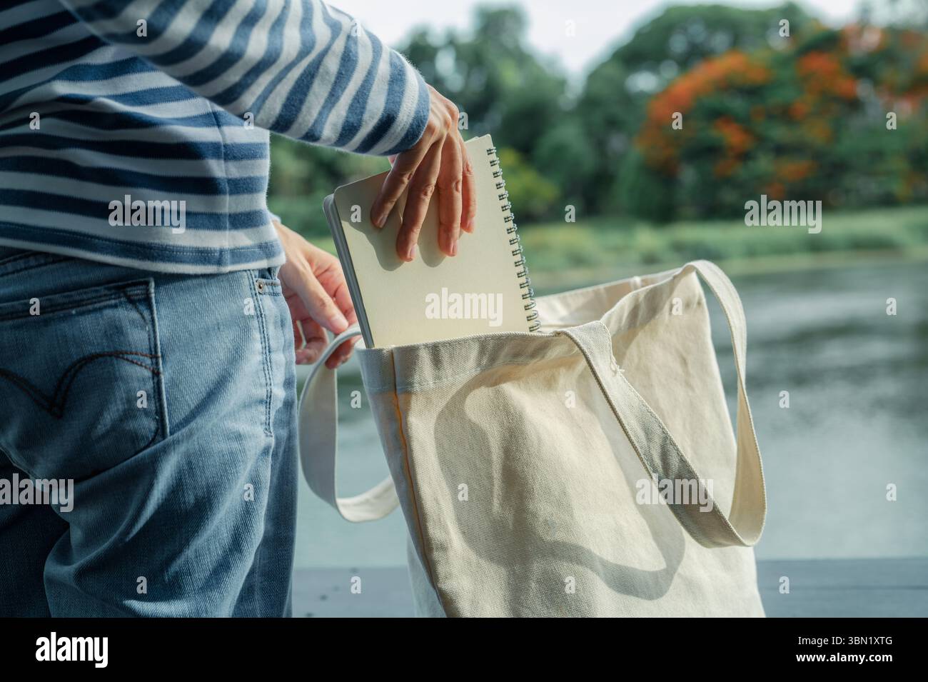 Femme plaçant le carnet dans le sac fourre-tout en toile durable. Mode écologique et vie consciente. Mode durable et style de vie minimaliste. Banque D'Images
