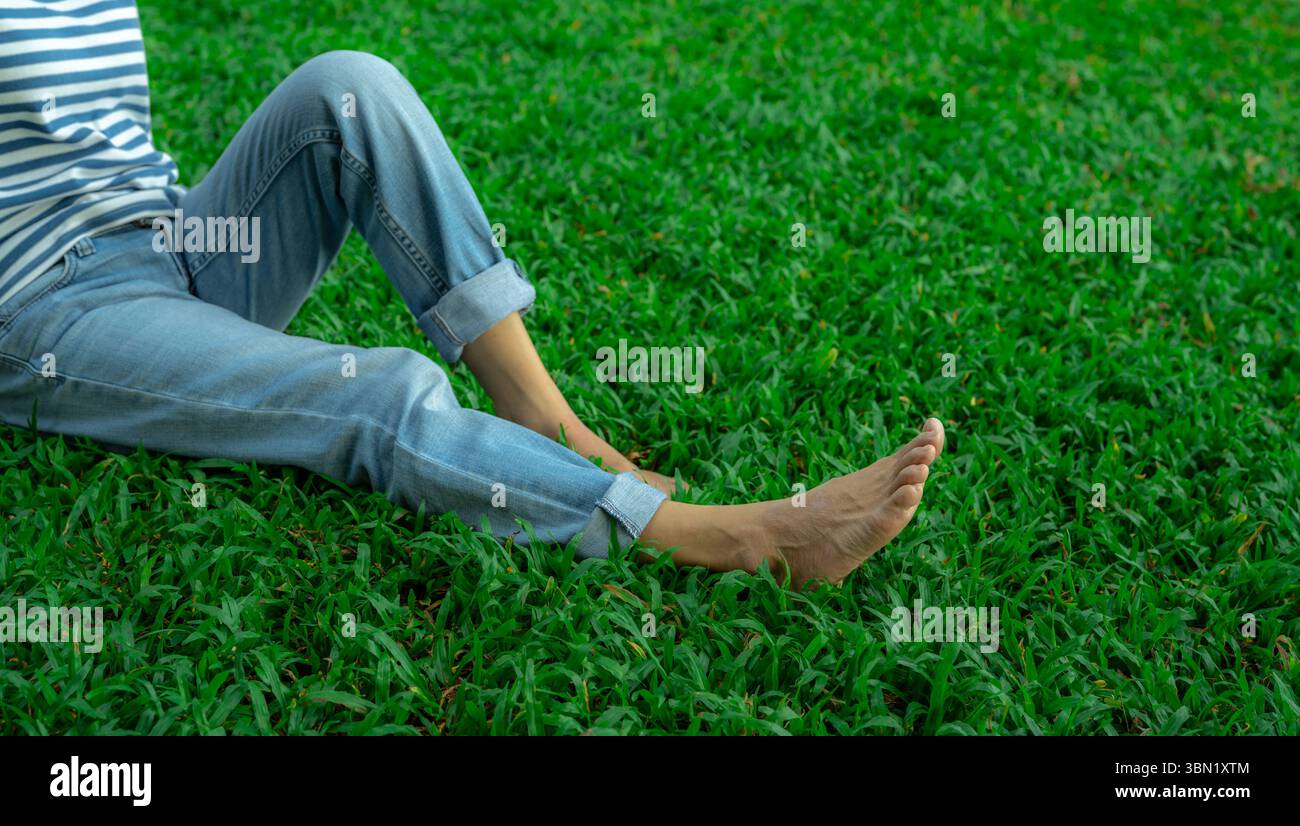 Femme détendue assise pieds nus sur la pelouse d'herbe verte fraîche. Guérison naturelle et soulagement du stress. Retraite paisible dans la nature. Santé mentale et bien-être Mindf Banque D'Images