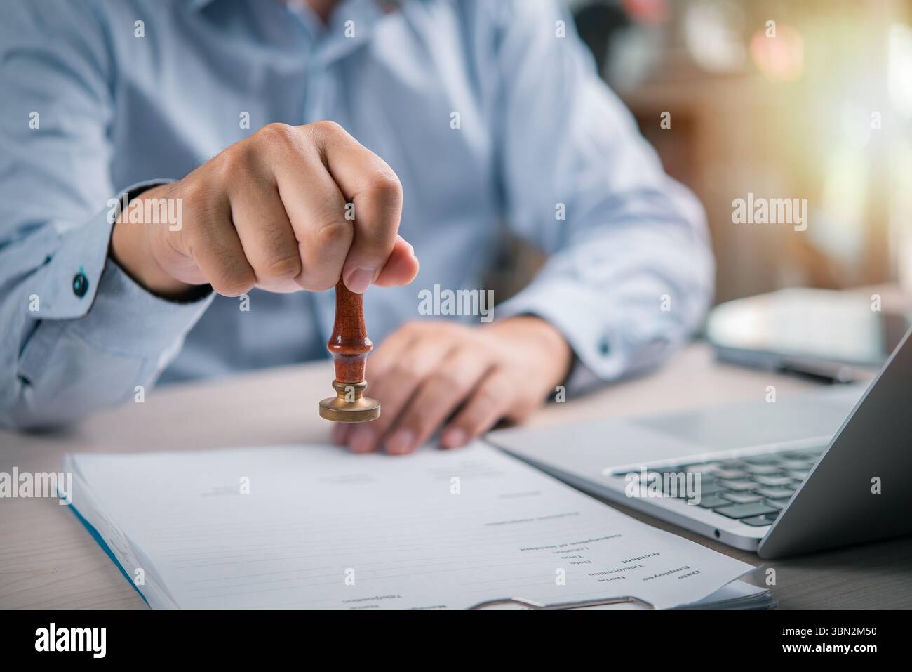 gros plan d'une main apposant un cachet légal à un contrat dans un bureau, signifiant l'approbation finale et l'authentification d'un document d'affaires important Banque D'Images