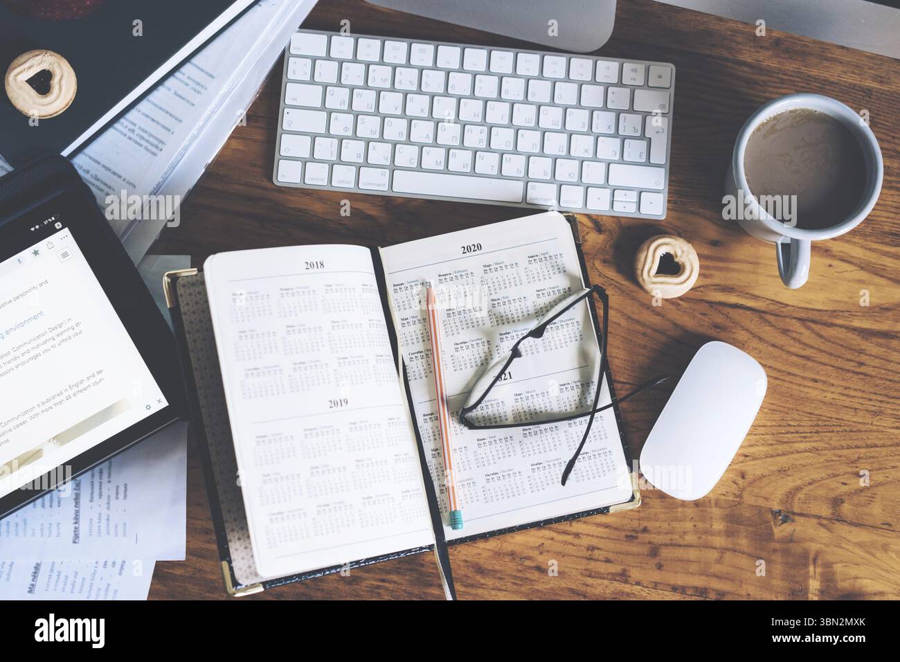 Gros plan d'un lieu de travail avec un clavier et des appareils et avec un journal ouvert sur la page. Recherche et planification de l'Internet offres favorables sur bankin Banque D'Images