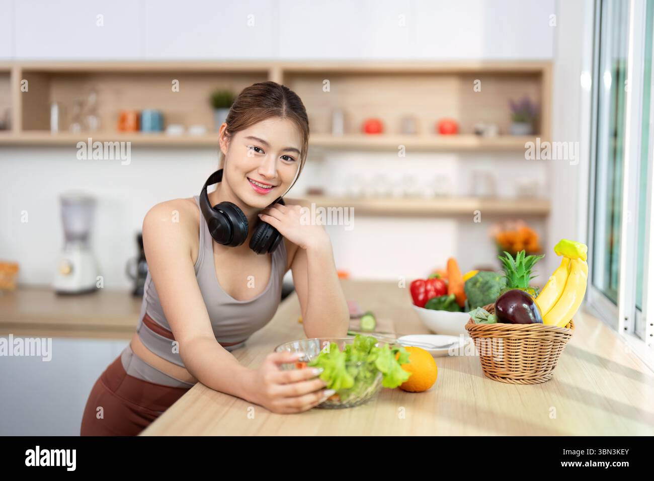 Bien-être et mode de vie sain. Jeune femme appréciant la salade fraîche tout en écoutant de la musique. Banque D'Images