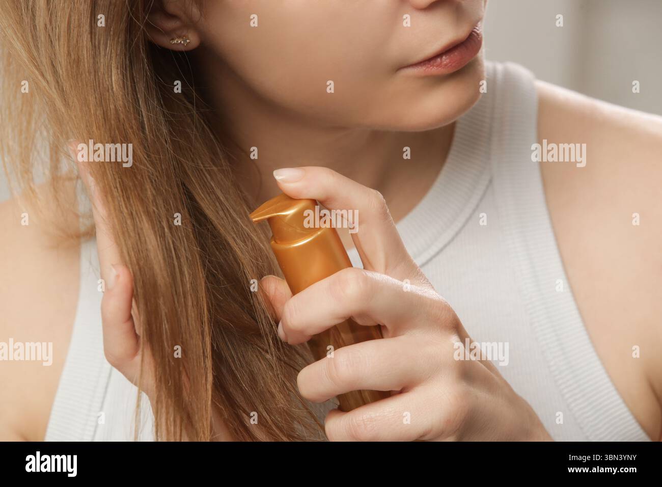 Femme appliquant de l'huile sur les extrémités des cheveux, pointes de cheveux fendus, cheveux secs ou concept de protection solaire Banque D'Images