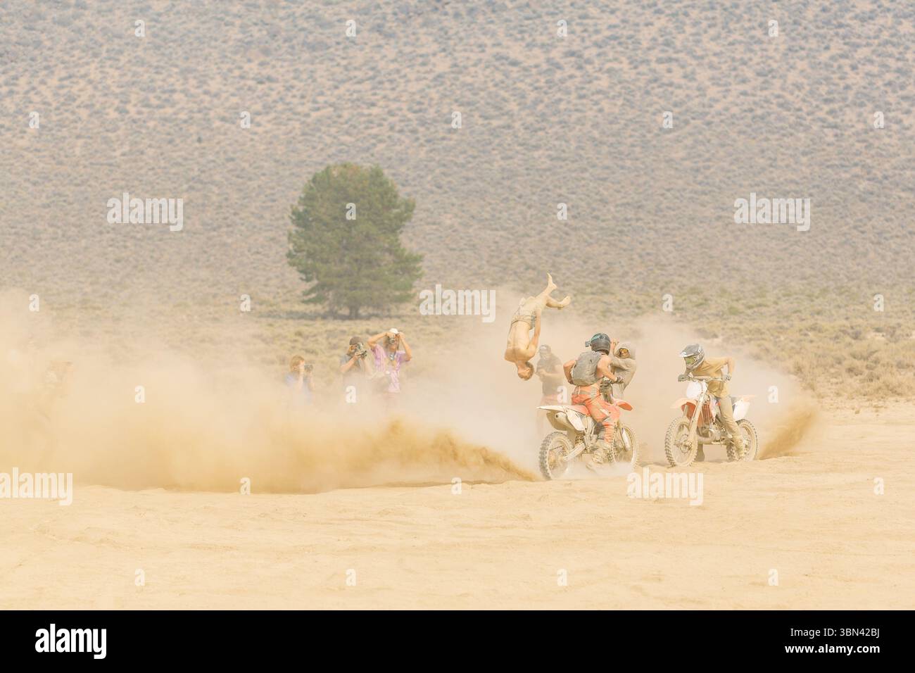 Pilote de motocross effectuant des cascades inversées dans une course dans le désert Banque D'Images