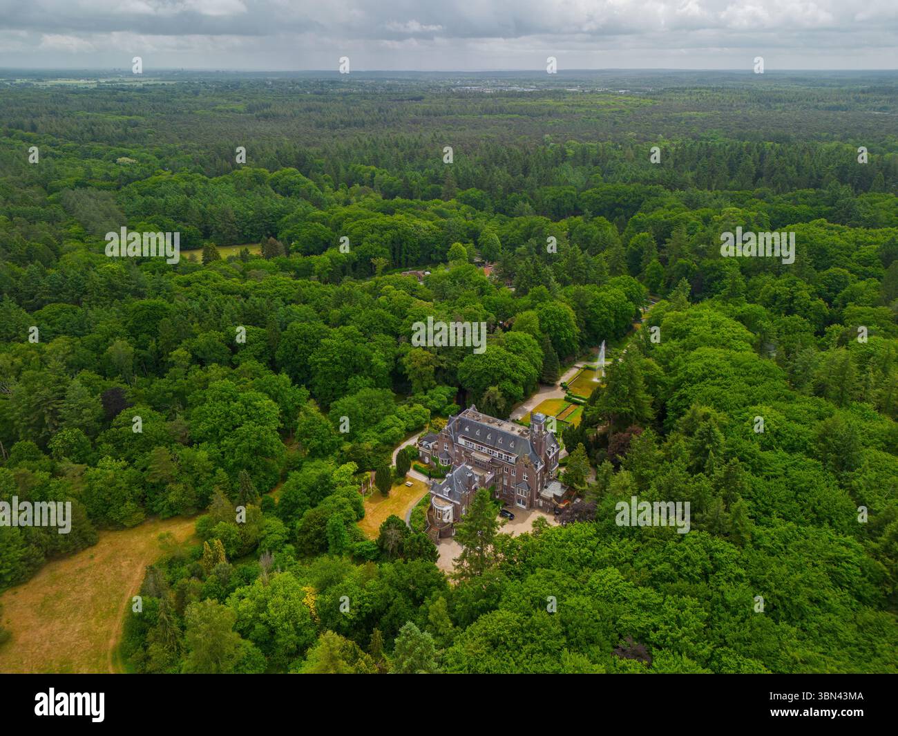 Une vue aérienne d'un manoir historique entouré d'arbres verdoyants et d'un jardin magnifiquement aménagé avec une fontaine, des sentiers pédestres et un parking Ar Banque D'Images