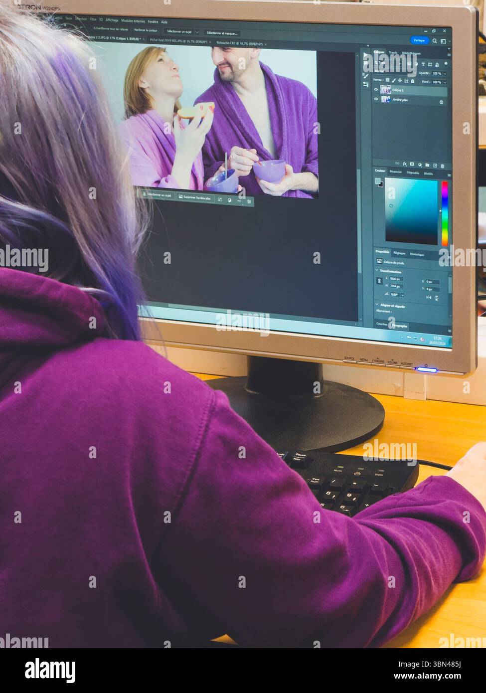 Jeune femme du dos avec des cheveux violets, travaillant sur Photoshop en infographie. Banque D'Images