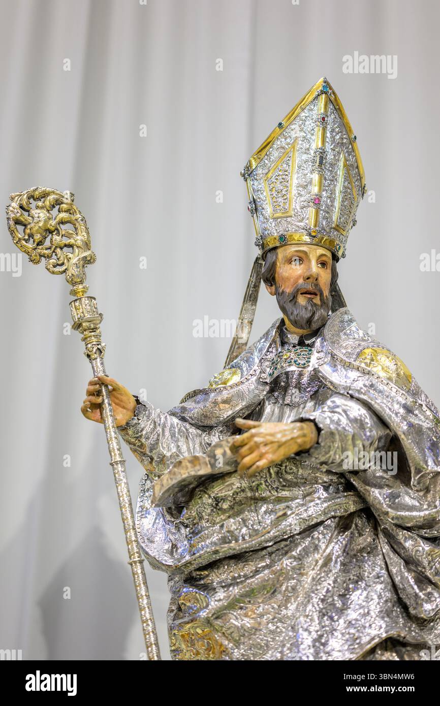Cette sculpture polychrome de Saint Isidore se dresse dans la cathédrale de Séville, ornée de vêtements argentés et entourée de fleurs et de bougies. Banque D'Images