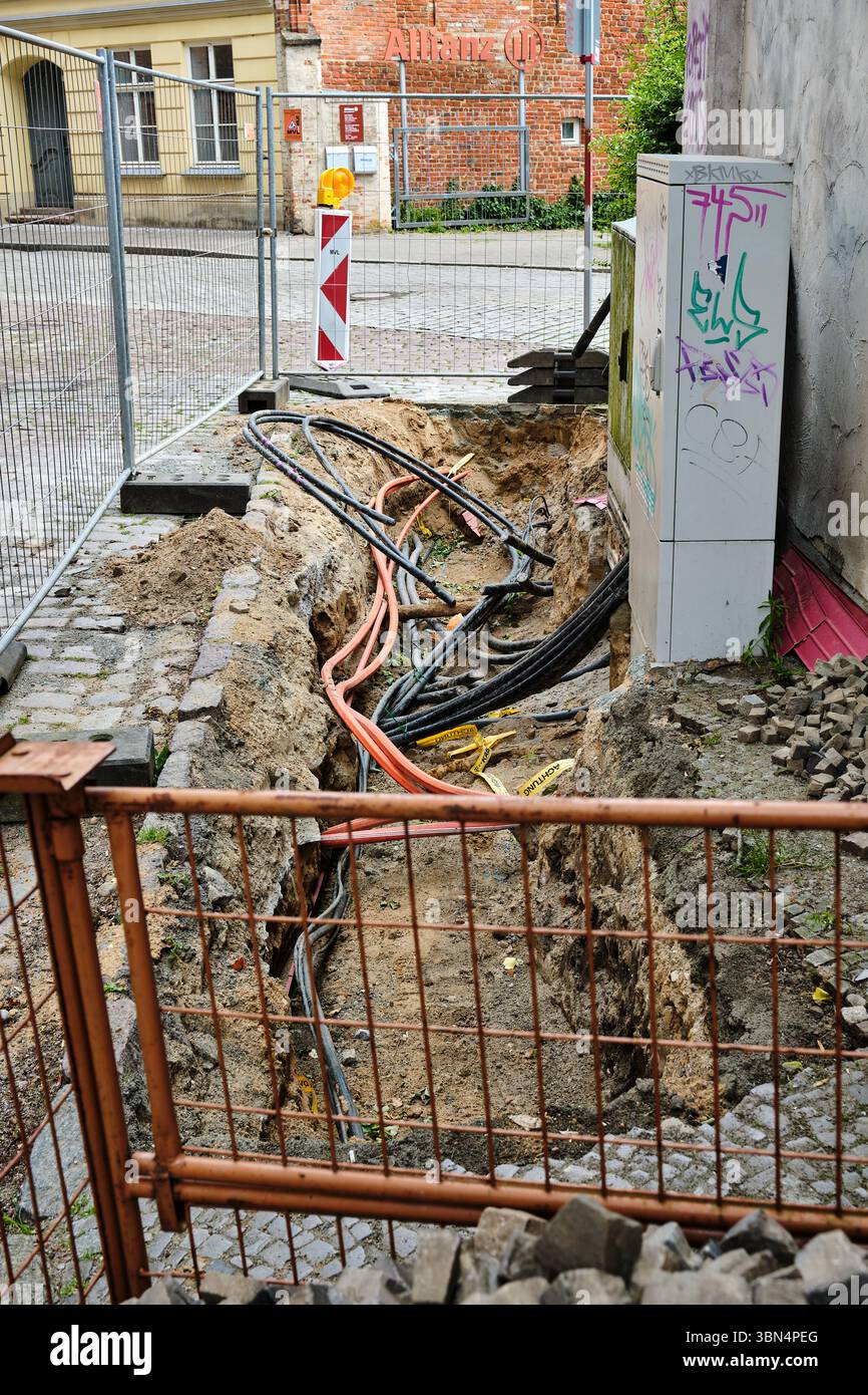 28 juin 2025 - Stralsund-Allemagne : une section de trottoir dans la vieille ville de Stralsund est ouverte pour des travaux d'alimentation souterraine, avec des câbles exposés Banque D'Images