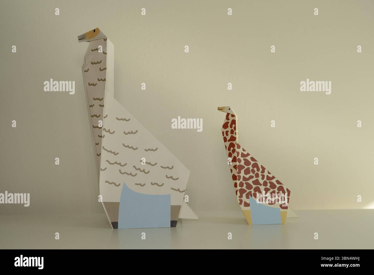 Girafes en papier origami debout sur une surface blanche Banque D'Images