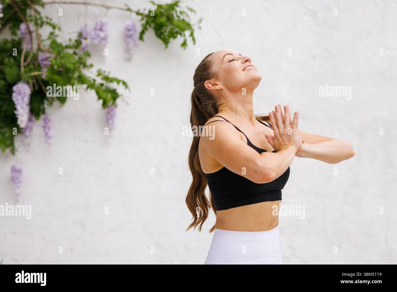 Femme souriante dans la pose de prière pratiquant le yoga et la pleine conscience en plein air pour le bien-être de soi et l'énergie positive Banque D'Images