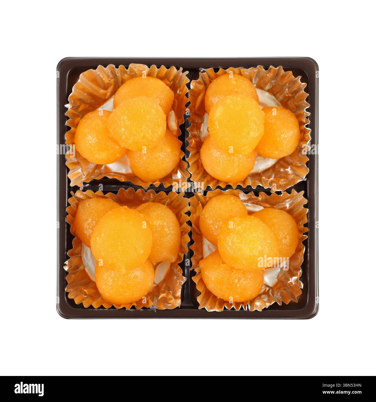 boules de caramel jaune d'oeuf cuites dans du sirop dans une boîte carrée isolée sur blanc, c'est un doux thaïlandais connu sous le nom de tong yod. Banque D'Images