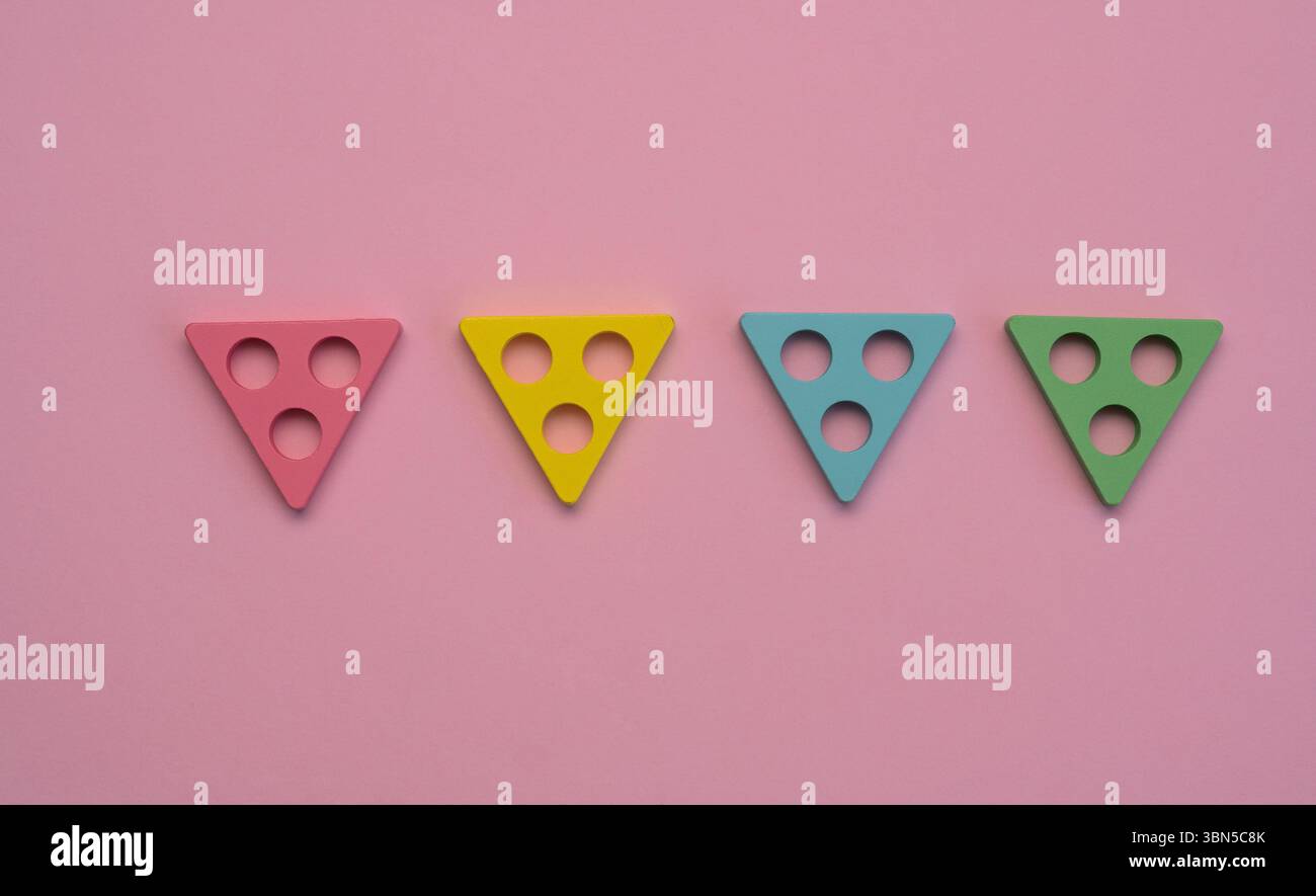 composition avec des formes triangulaires vibrantes symbolisant l'ordre et la structure. Quatre triangles géométriques colorés avec des trous circulaires placés en rangée sur b rose Banque D'Images