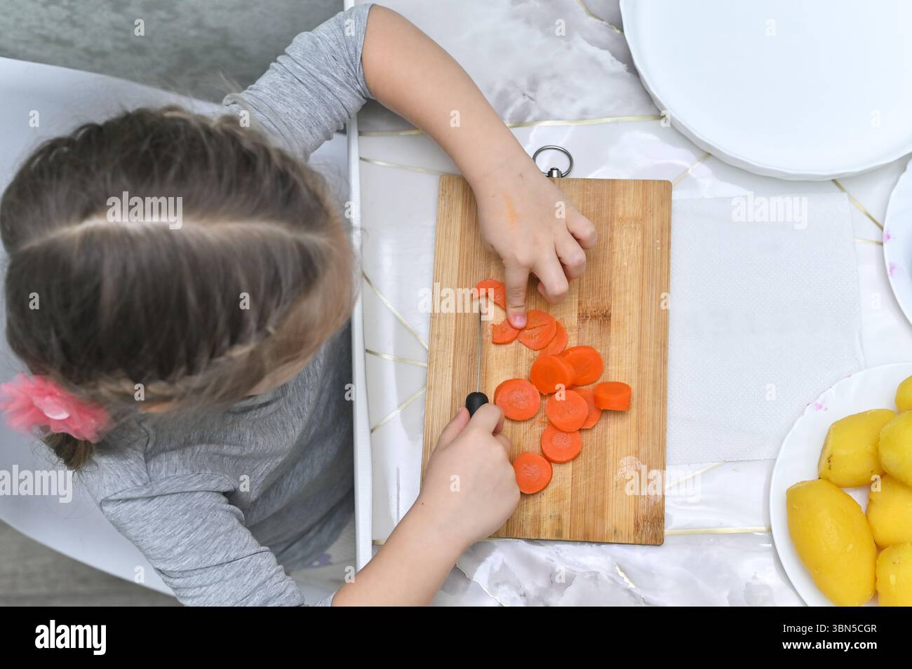 De la cuisine de jeu à la vraie cuisine, la fille obtient son diplôme à l'utilisation d'ingrédients réels. pour obtenir du contenu sur la façon d'encourager la participation des enfants au cho de ménage Banque D'Images