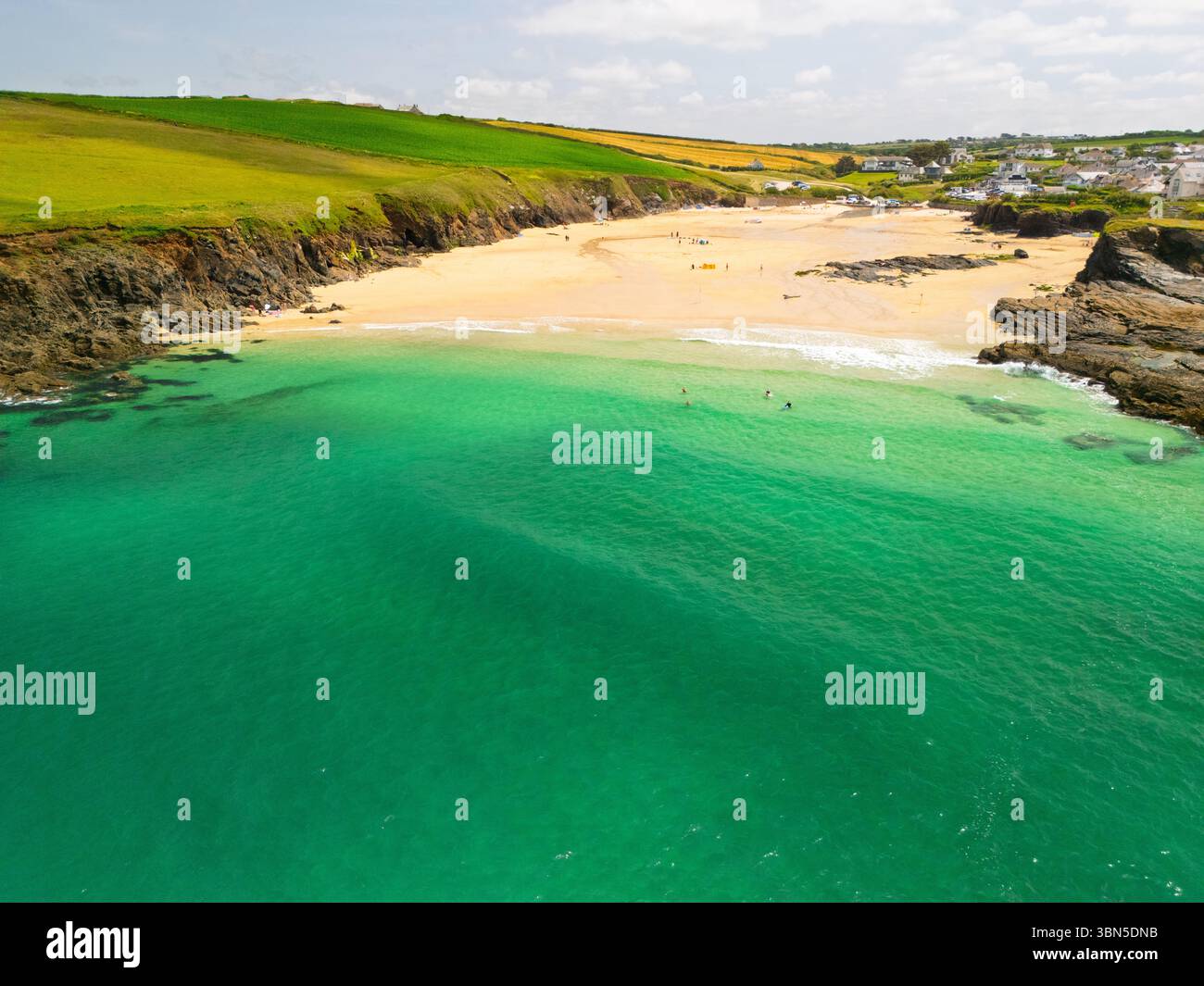 Une vue aérienne des gens profitant d'une journée ensoleillée sur une plage avec une eau turquoise claire, rivage de sable et falaises verdoyantes. Banque D'Images