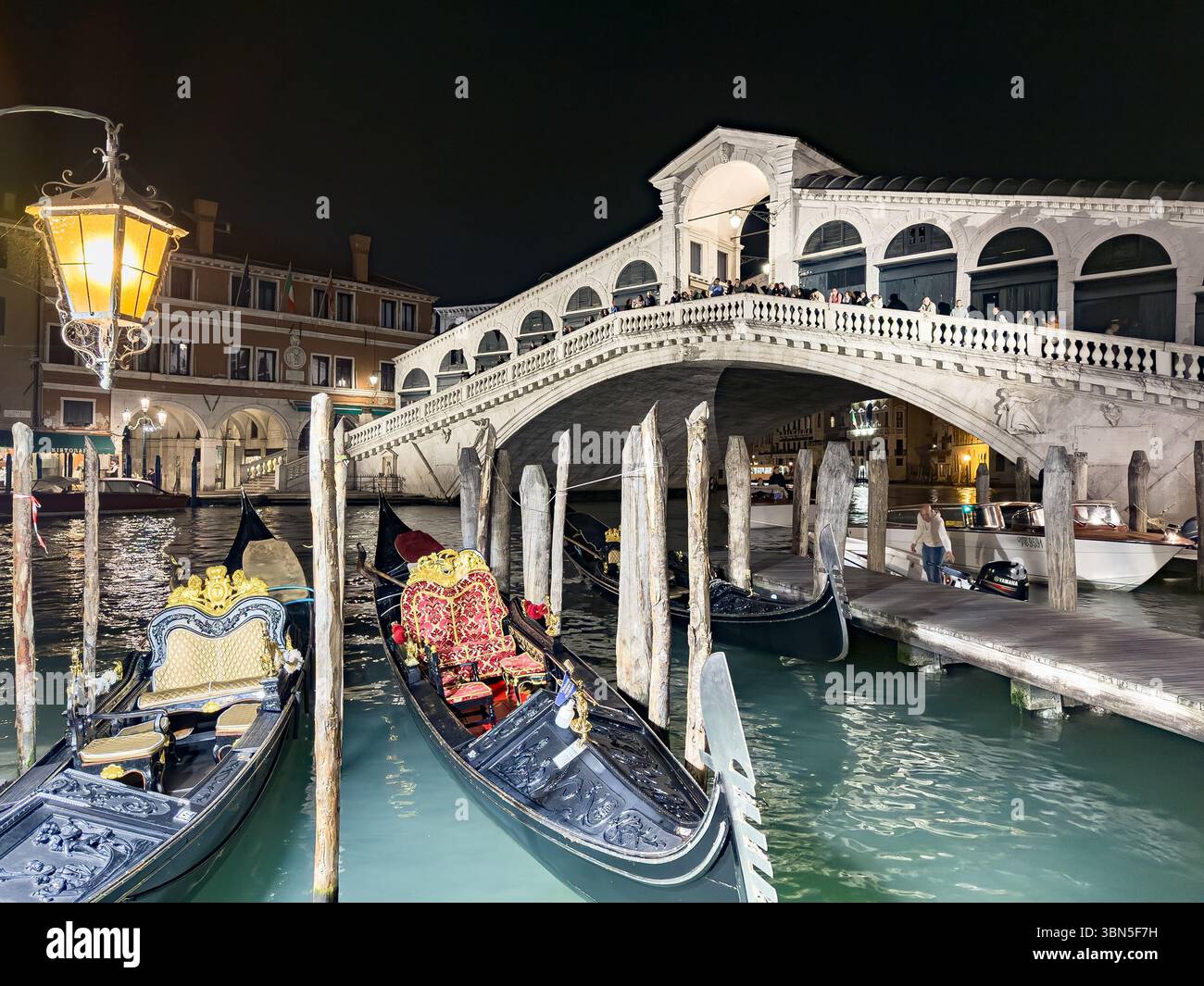 Venise, Italie - 1 novembre 2024 : Ponte di Rialto et le port avec bateau taxi et touristes à Venise, Italie la nuit, lampe jaune Banque D'Images