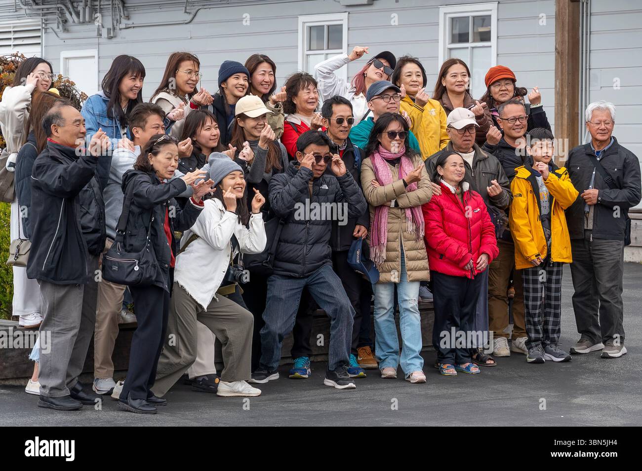 Groupe de touristes japonais posant pour une photo près de l'emblématique Pier 39 de San Francisco par une journée ensoleillée. Banque D'Images
